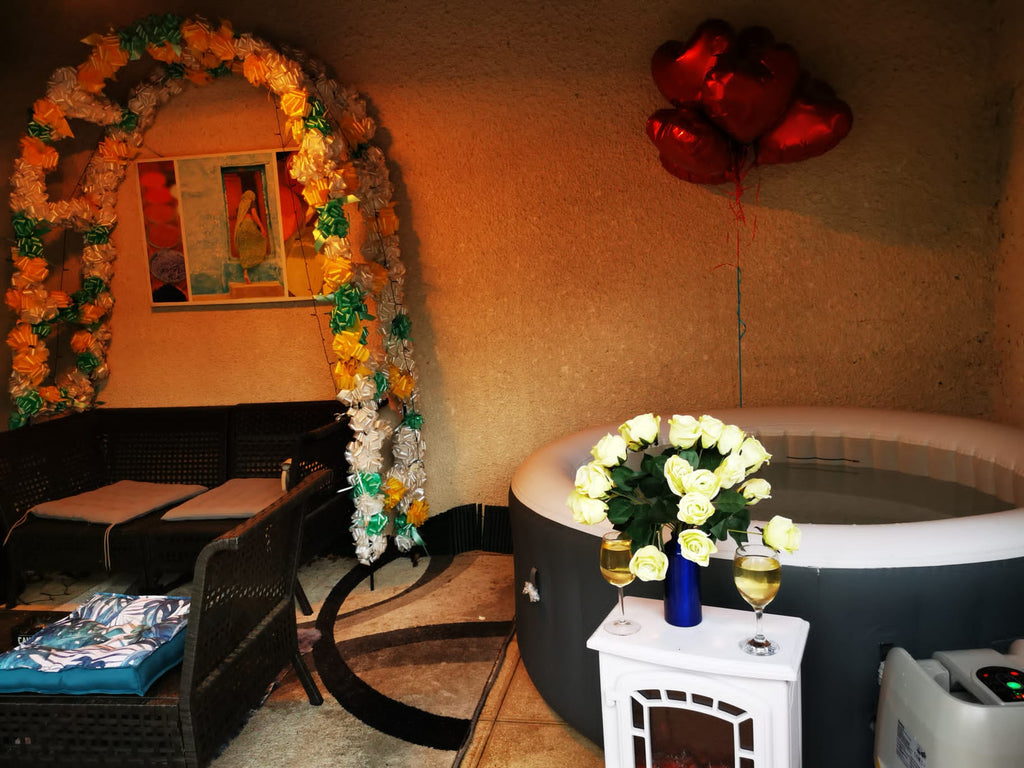 Jacuzzi derrière un meuble avec une fleur, des ballons en arrière plan, ambiance festive.